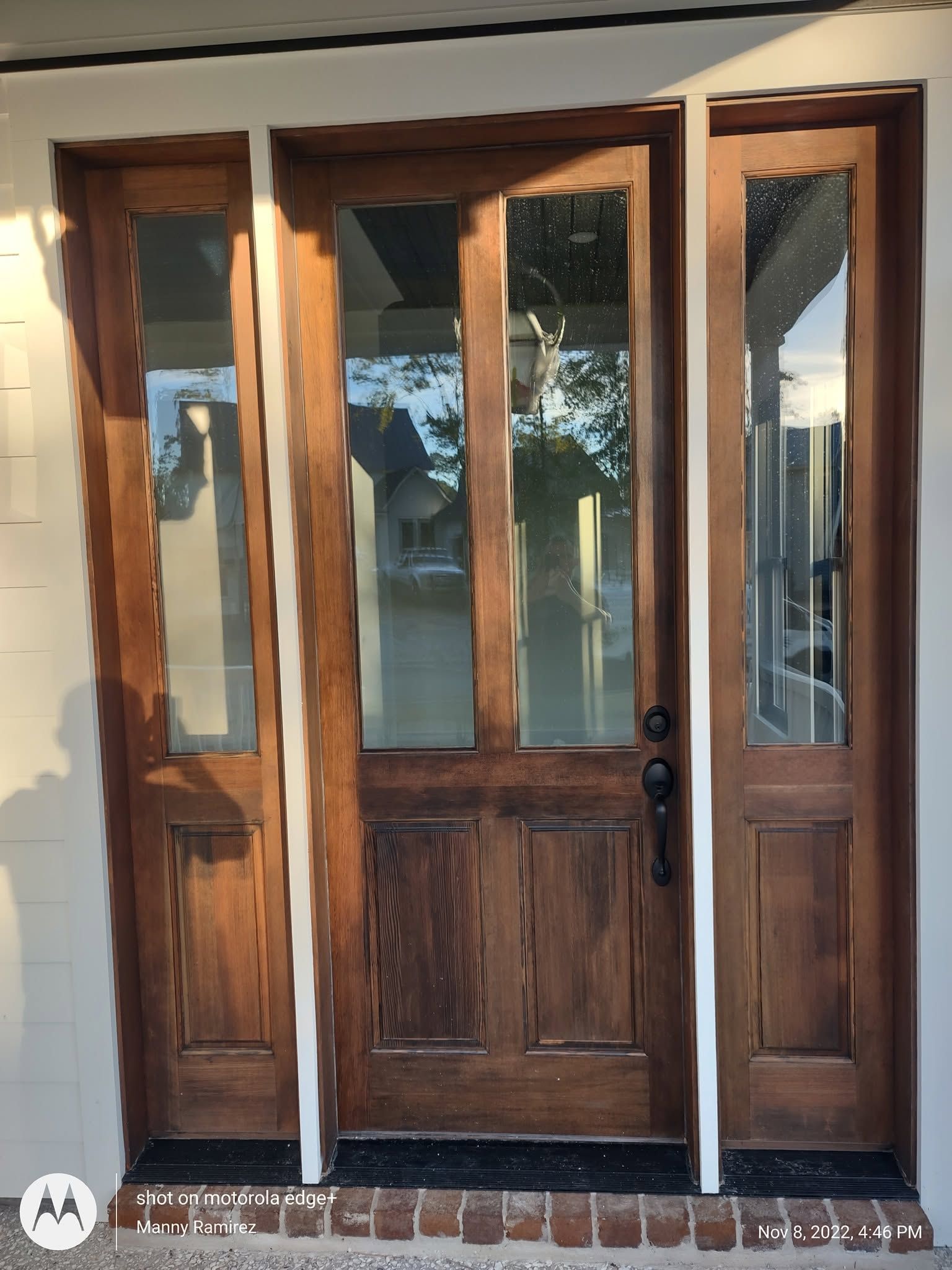 Refinished front door with warm walnut stain and crisp white trim surround