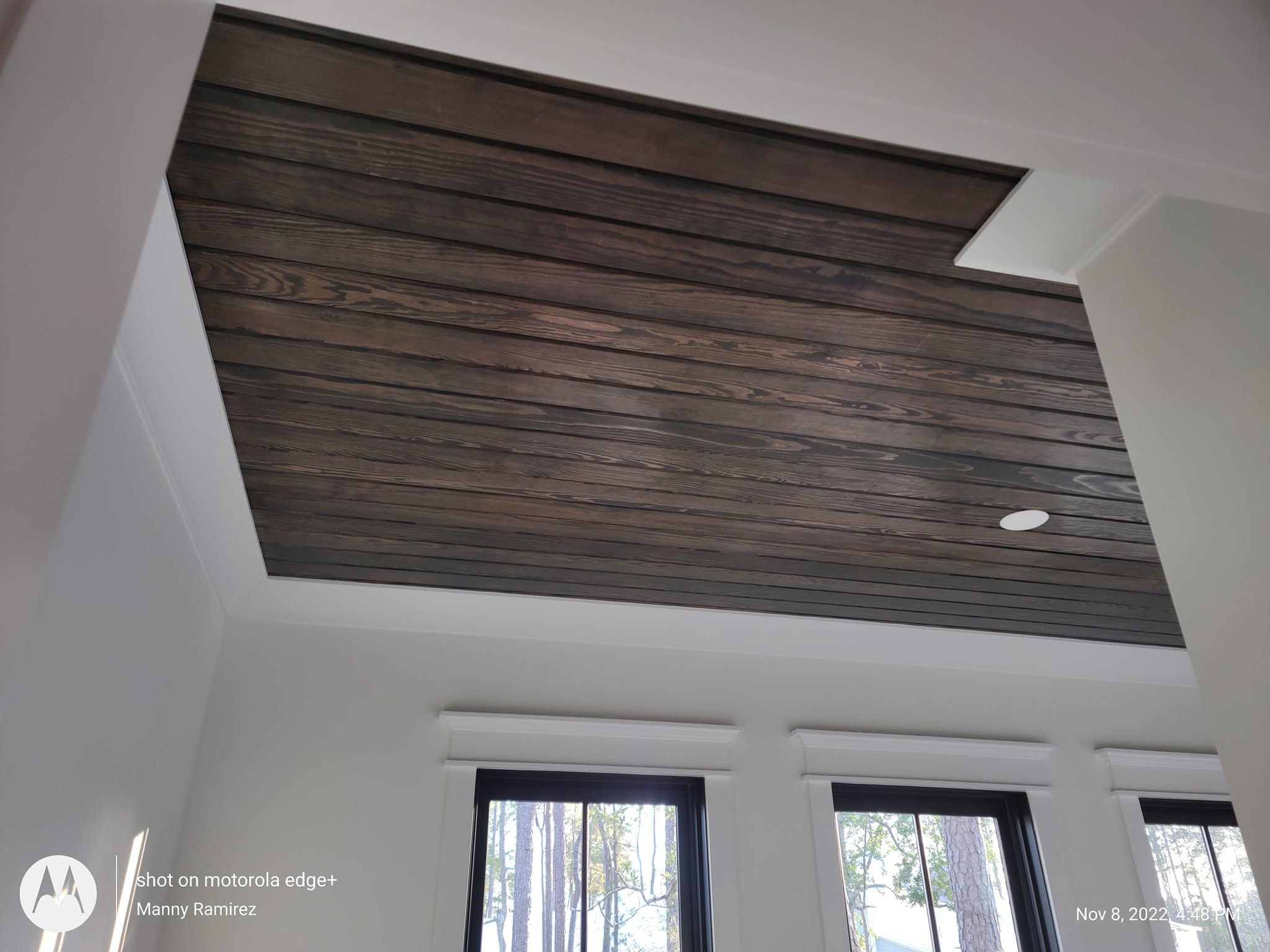 Dark espresso-stained tongue-and-groove wood plank ceiling with recessed lighting