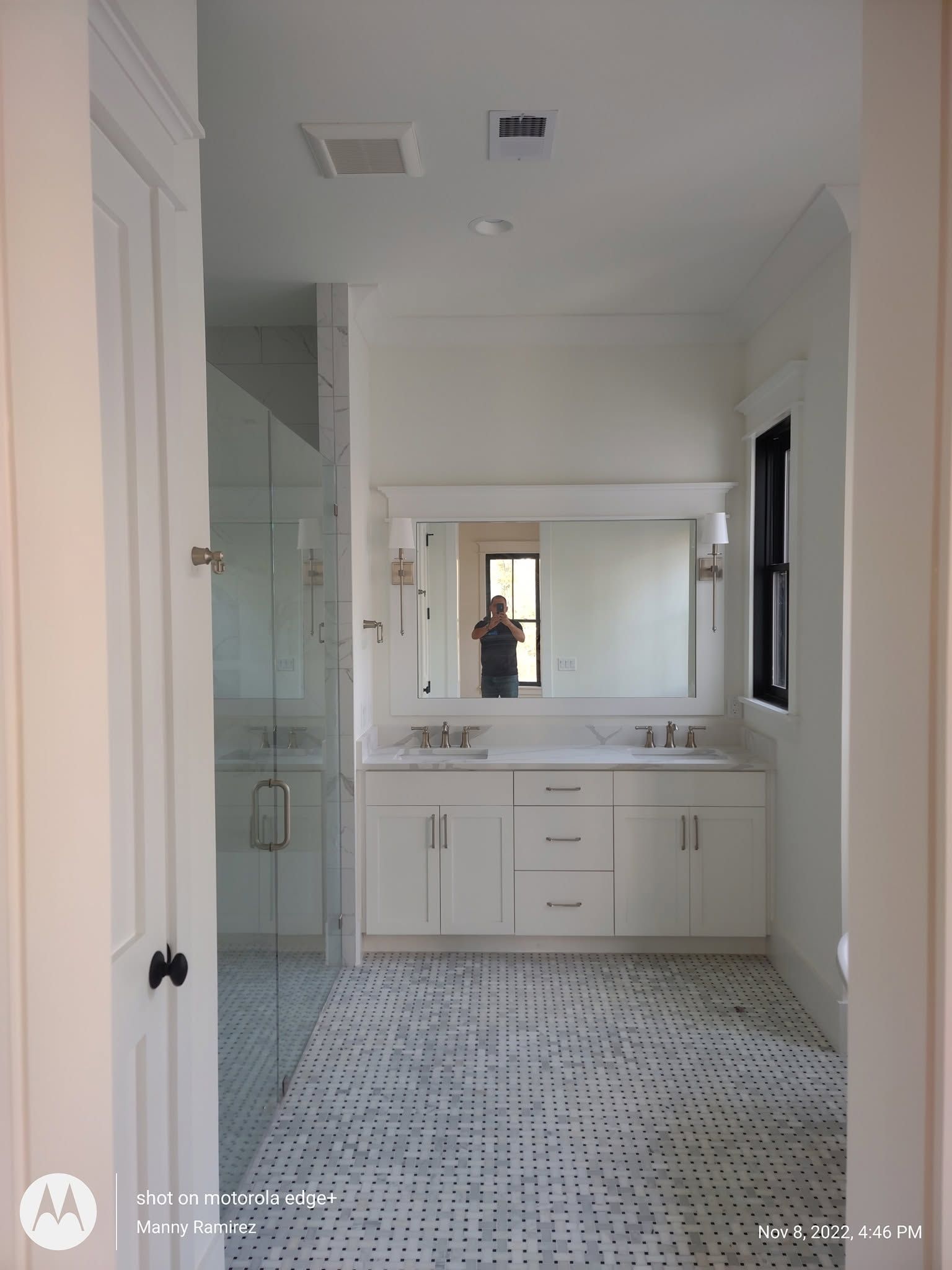 White painted primary bathroom with marble penny-tile floor and double vanity