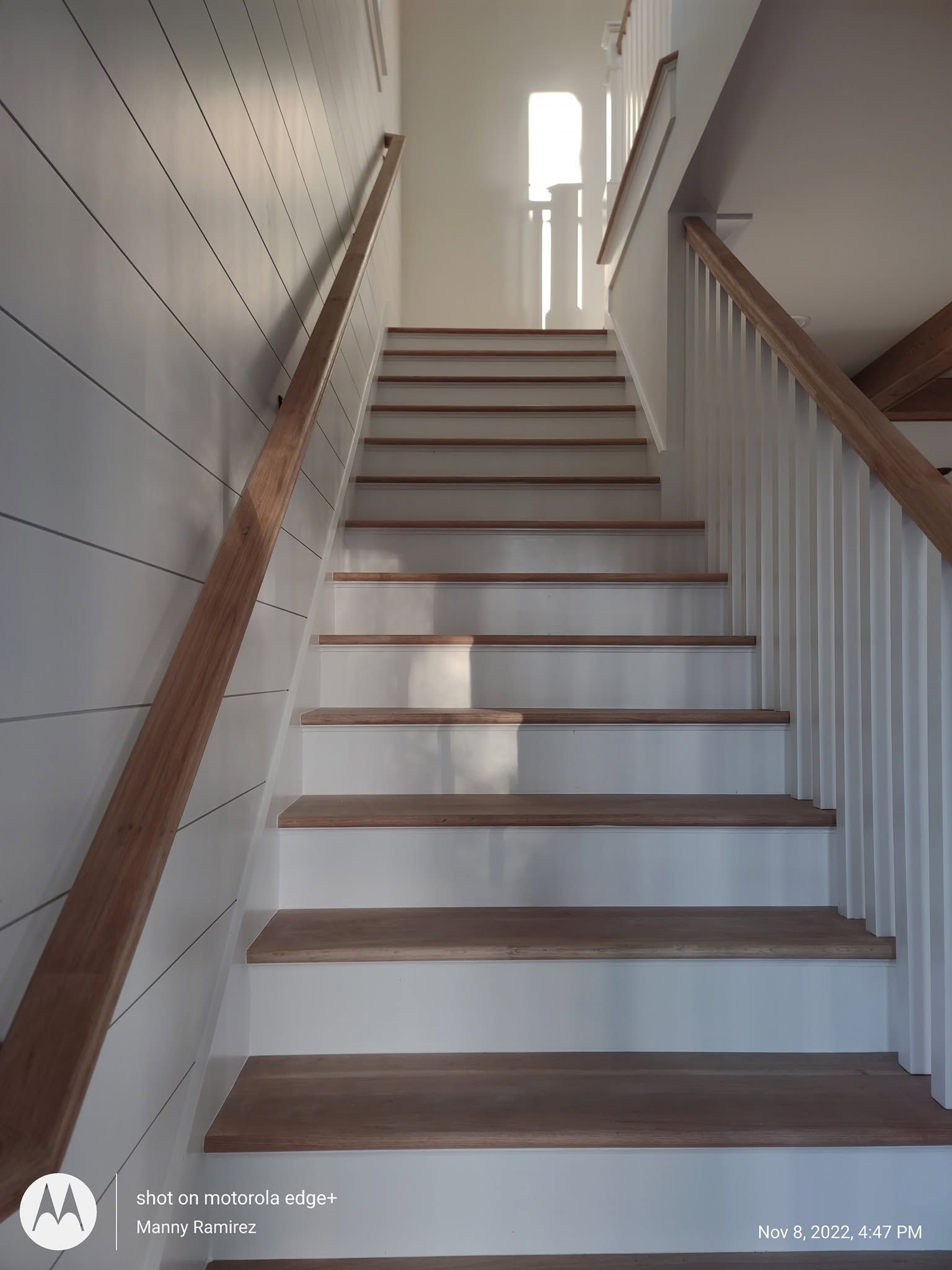 White shiplap stairwell with natural wood treads and white risers