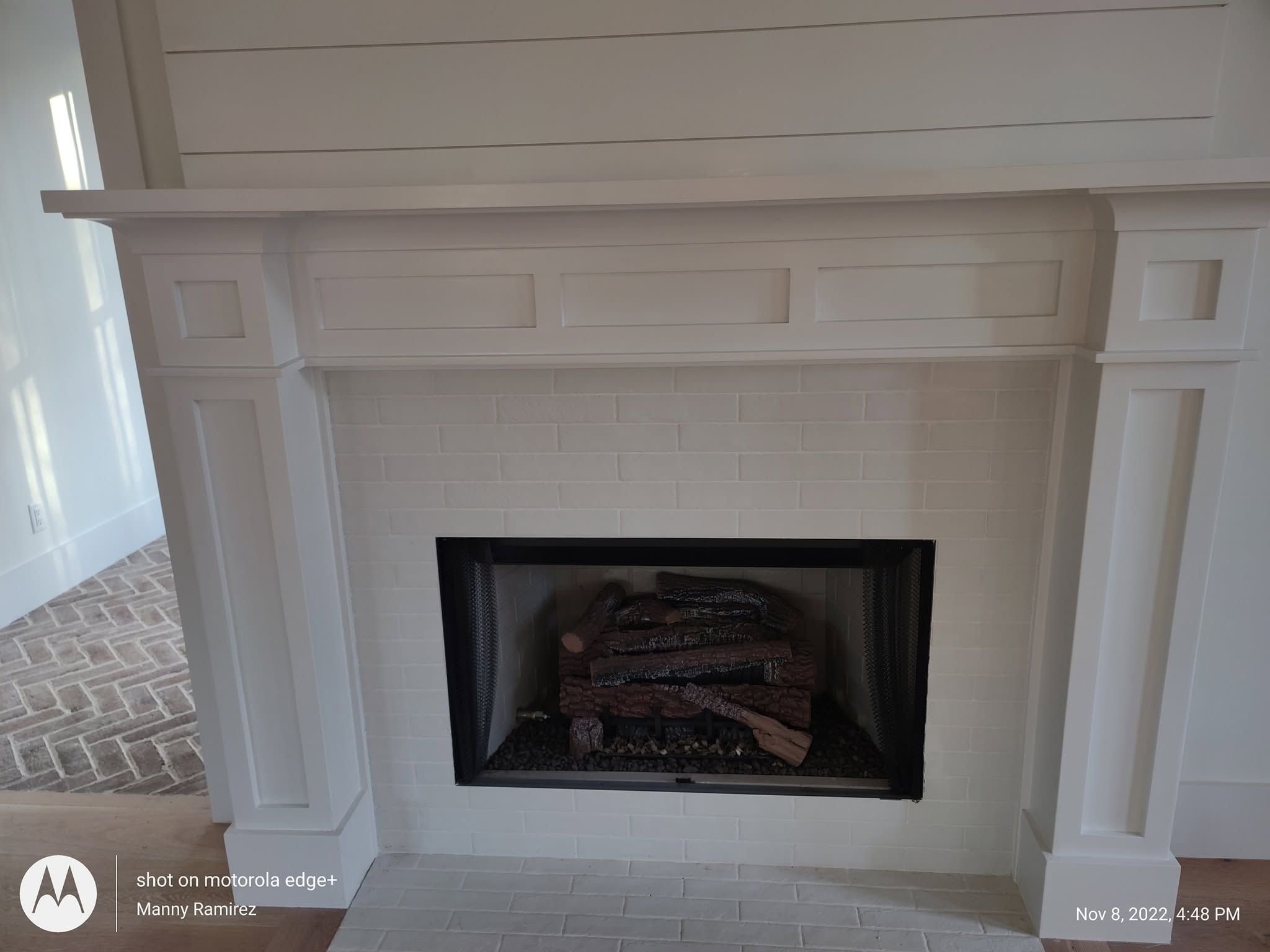 White painted fireplace mantel with subway-tile surround and black firebox