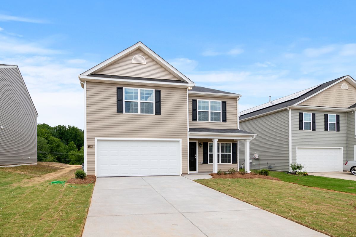 A two-story new-construction home with tan hardi-plank siding and a covered front porch, typical of new builds in Okatie, SC