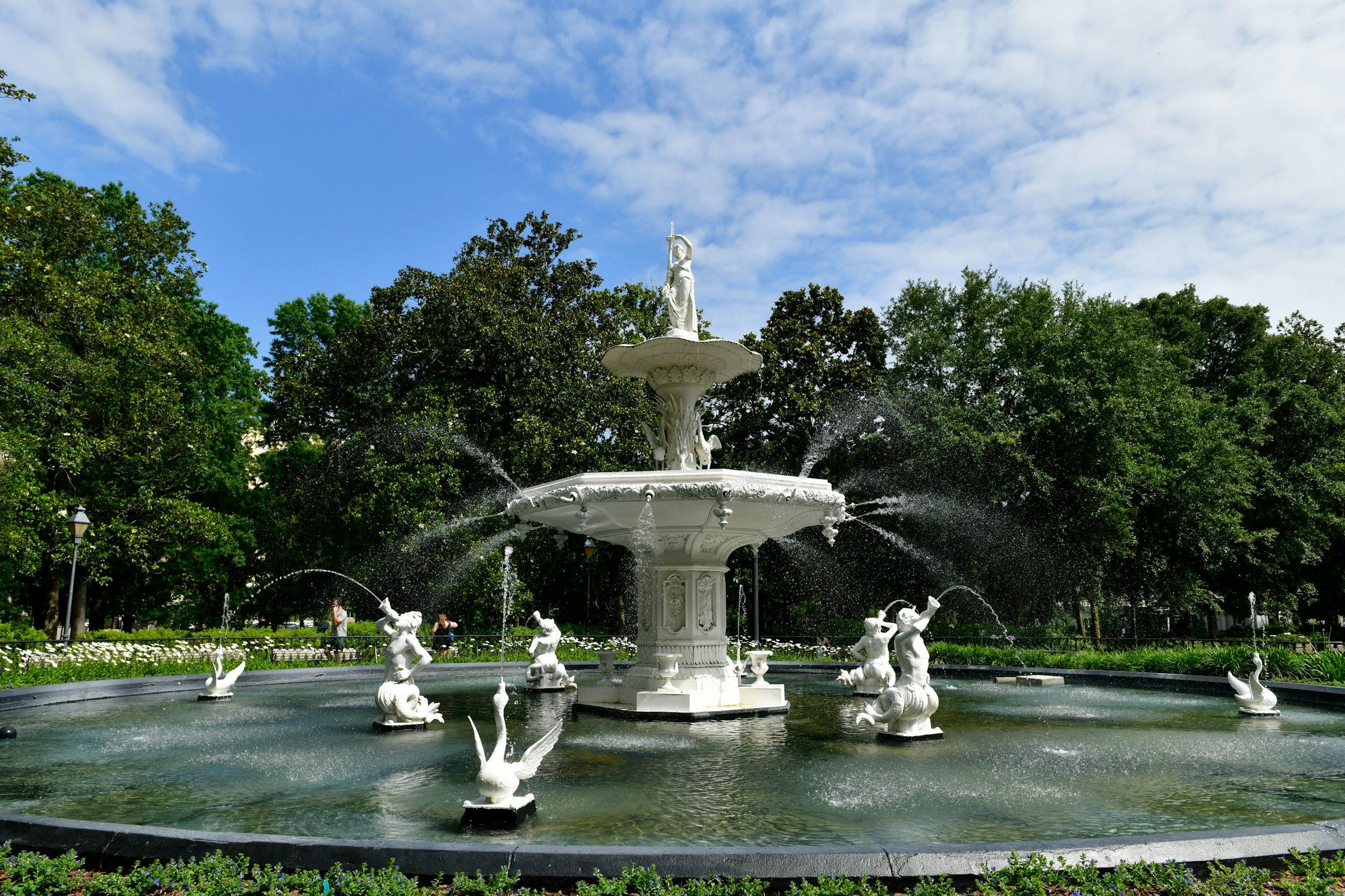 The ornate white Forsyth Park fountain in Savannah, GA, framed by live oak trees